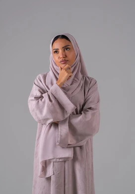 بورتريه لإمرأة عربية خليجية سعودية  ترتدي العباءة والحجاب تضع يدها على ذقنها، ايماءات التفكير والحيرة، مفهوم التأمل والتخطيط، تعابير التمعن والتركيز، خلفية رمادية