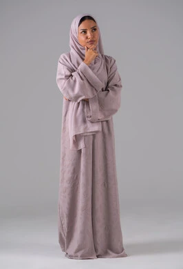 تعابير التمعن والتركيز، مفهوم التأمل والتخطيط،بورتريه لإمرأة عربية خليجية سعودية  ترتدي العباءة والحجاب تضع يدها على ذقنها، ايماءات التفكير والحيرة، خلفية رمادية