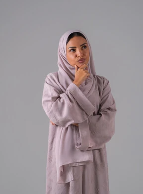 The concept of contemplation and planning, expressions of reflection and focus, a portrait of a Saudi Gulf Arab woman wearing an abaya and hijab, resting her hand on her chin, gestures of thought and confusion, gray background.