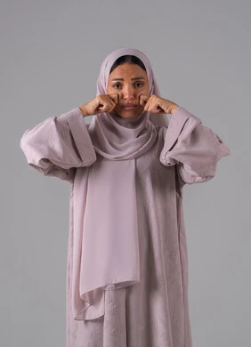 الندم والحسرة على شيء ما، مفهوم القهر والخسارة، بورتريه لامرأه عربيه خليجيه سعوديه ترتدي العباءة والحجاب تضع يدها على وجهها بإيماءات الحزن، الشعور بالإنزعاج والخذلان، خلفية رمادية