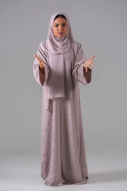 الإستغراب والاستفسار عن أمر ما، الإستفهام حول موضوع معين, بورتريه لامراه عربيه خليجيه سعودية ترتدي العباءة والحجاب تنظر الى الكاميرا وترفع يديها نحو الأعلى بإيماءات عدم المعرفة والحيرة ، الغموض وعدم الوضوح، خلفية رمادية