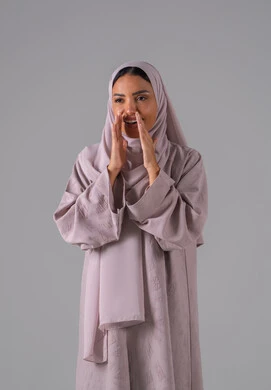 A portrait of a Gulf Arab Saudi woman wearing an abaya and hijab, placing her hand on her mouth with gestures indicating calling, the concept of chats and conversations, calling and speaking loudly, with a gray background.