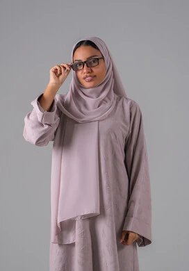 بورتريه لامرأة عربية خليجية سعودية ترتدي العباءه والحجاب والنظارات الطبيه بايماءات السرور والسعادة،مفهوم ضعف البصر، الاناقة والاهتمام بالمظهر الخارجي،  خلفية رماديه