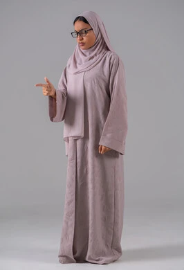 مفهوم ضعف البصر، الاناقة والاهتمام بالمظهر الخارجي، بورتريه لامرأة عربية خليجية سعودية ترتدي العباءه والحجاب والنظارات الطبيه بايماءات السرور والسعادة، خلفية رماديه