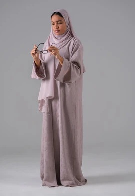 ايماءات التركيز والاندماج ،مفهوم ضعف البصر، الاناقة والاهتمام بالمظهر الخارجي، بورتريه لامرأة عربية خليجية سعودية ترتدي العباءه والحجاب والنظارات الطبيه  ، خلفية رماديه