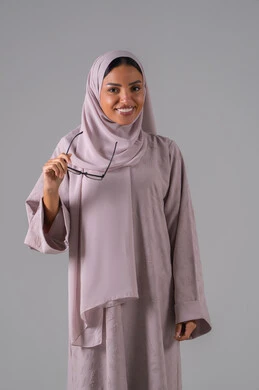 الاهتمام بالمظهر الخارجي، مفهوم ضعف البصر، بورتريه لامرأة عربية خليجية سعودية ترتدي العباءه والحجاب والنظارات الطبيه بايماءات السرور والسعادة ، خلفية رماديه