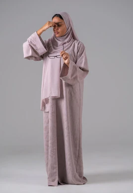 The feeling of fatigue and exhaustion, the concept of poor eyesight, elegance and attention to appearance, a portrait of a Saudi Gulf Arab woman wearing an abaya, hijab, and prescription glasses with gestures of interaction and integration, gray background.