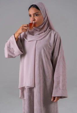 الاستمتاع في تناول المشروبات الساخنه ، تعابير الجودة والامتياز ، النظر بإيماءات السعادة ، مفهوم الاهتمام بالمظهر الخارجي، منتجات محلية وطنية سعودية، بورتريه لامراة عربيه خليجية سعودية ترتدي العباءة والحجاب تحمل بيدها كوب من الشاي، خلفية رمادية