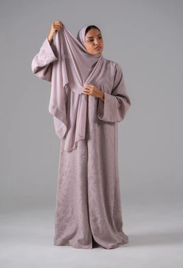 أزياء محجبات عصرية أنيقة, الاهتمام بالأناقة والمظهر الخارجي, مفهوم الأنوثة والنعومة, بورترية لشابة عربية خليجية سعودية ترتدي العباءة وتعدل من وضعية الحجاب تقف بتعابير الثقة والاعتزاز بالنفس ، خلفية رمادية