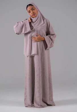 Gestures of distress and pain, neck, bone, and spine pain, a portrait of a Saudi Gulf Arab woman wearing an abaya and hijab holding her neck with gestures of pain, the necessity to go to the doctor and receive treatment, gray background.