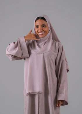 حركة يد تدل على الاتصال، الاهتمام بالمظهر الخارجي والوسامة، تلقي أخبار سارة عبر الجوال، مفهوم تبادل المعلومات، بورتريه لامراه عربيه خليجيه سعودية ترتدي العباءة والحجاب ترفع يدها بايماءات الرد على المكالمات الهاتفية، الجسم بالطول الكامل، خلفية رمادية