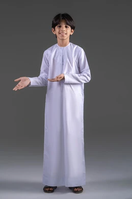 عرض و تقديم عنصر ما، حمل العناصر ورفعها، استخدام حاسة اللمس لتحريك العناصر الهولوجراميه، بورتريه لولد عربي خليجي سعودي يرتدي الثوب التقليدي الابيض ينظر الى الكاميرا يرفع يده الى الأمام بايماءات حمل شيء، صورة الجسم بالطول الكامل، خلفية رمادي