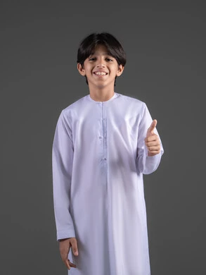 Expressions of agreement and acceptance, looks of joy and feelings of satisfaction, a portrait of a Saudi Arabian Gulf boy wearing a traditional white thobe, raising his thumb up as a sign of quality, standing upright and looking at the camera with gestures of interaction, full-body image, gray background.