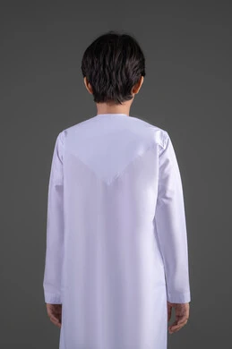 التجهز والاستعداد  للذهاب للخارج،  الاهتمام في المظهر الخارجي، النظر الى الكاميرا بايماءات السعادة و السرور، بورترية من الخلف لولد عربي خليجي سعودي يرتدي الثوب التقليدي الابيض , ايماءات الوسامة والرجولة منذ الصغر, الجسم بالطول الكامل ، خلفية رمادي