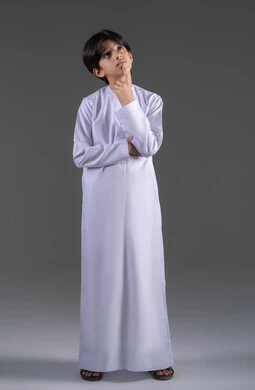 التأمل والتخطيط للمستقبل، إيجاد حل لمشكلة ما، التركيز وشرود الذهن والتمعن، بورتريه لولد عربي خليجي سعودي يرتدي الثوب الابيض التقليدي يقف باستقامة و يقوم بوضع يده على ذقنه و ينظر إلى الكاميرا بإيماءات التفكير، صورة الجسم بالطول الكامل، خلفية رمادي