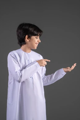 تقديم وعرض عنصر ما، رفع وحمل العناصر، استخدام حاسة اللمس لتحريك العناصر الهولوجراميه، بورتريه لولد عربي خليجي سعودي يرتدي الثوب التقليدي الابيض ينظر الى الكاميرا يرفع يده الى الأمام بايماءات حمل شيء، الإشارة إلى كف اليد, خلفية رمادي