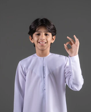 تعابير الإعجاب والرضى، علامة الامتياز و الجودة، بورتريه لولد عربي خليجي سعودي مبتسم يرتدي الثوب الابيض التقليدي يرفع يده بإيماءات تدل على القبول و الموافقة، النظر إلى الكاميرا بإشارات الموافقه، الشعور بحالة جيدة, الاناقة و الاهتمام بالمظهر الخارجي، خلفية رمادي