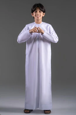 التعبير عن المشاعر الإيجابية، مفهوم السعادة والطمأنينه والمحبه, بورتريه لولد عربي خليجي سعودي مبتسم يرتدي الثوب التقليدي الابيض يقوم برفع يديه على شكل قلب, النظر الى الكاميرا بإيماءات الشعور بالحب, الاحتفال بعيد الحب (الفالنتاين)، الطول الكامل للجسم، خلفية رمادي