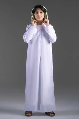 التسلية والترفيه بإستخدام تقنية الهيدفون، سماع الموسيقى والصوتيات، ارتداء سماعات الرأس الصوتية، بورتريه لولد عربي خليجي إماراتي يرتدي الكندورة الإماراتية يقوم بالاستماع للأغاني بايماءات السرور والسعاة، خلفية رمادية