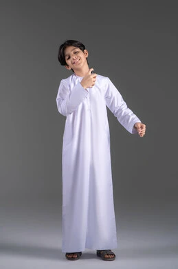 مفهوم التعطر والتطيب, التسويق لمنتجات العطور، عطورات خليجية اماراتية , الاهتمام بالمظهر الخارجي, استخدام الزيوت العطرية الطبيعية, بورتريه لولد عربي خليجي اماراتي يرتدي الزي التقليدي يقوم برش العطر, صورة الجسم بالطول الكامل, خلفية سوداء