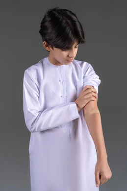 دور الضمادات الطبية في تخفيف الألم, إيماءات تدل على وجود الأوجاع, بورتريه لفتى عربي خليجي اماراتي يرتدي الكندورة يشير إلى لصاقة صغيرة موجودة على يده, خلفية رمادية دور الضمادات الطبية في تخفيف الألم, إيماءات تدل على وجود الأوجاع, بورتريه لفتى عربي خليجي اماراتي يرتدي الكندورة يشير إلى لصاقة صغيرة موجودة على يده, خلفية رمادية