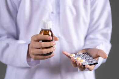 مفهوم الاستفادة من الدواء الموصوف, الالتزام باتخاذ الأدوية في الوقت المناسب لها, بورتريه مقرب لفتى عربي خليجي اماراتي يرتدي الكندورة يحمل زجاج دواء عاتمة وشريط  حبوب، الإصابة بالمرض والتوعك, خلفية بيضاء