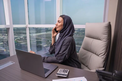 إنجاز المهام عن بعد باستخدام الجوال، الاستمتاع بتبادل الأحاديث و الأخبار، امراه عربيه خليجيه اماراتية ترتدي العباءة و الحجاب تجلس على المكتب تقوم بإجراء مكالمة هاتفيه باستخدام الهاتف المحمول, بيئة عمل مريحة في الشركات الاماراتية إنجاز المهام عن بعد باستخدام الجوال، الاستمتاع بتبادل الأحاديث و الأخبار، امراه عربيه خليجيه اماراتية ترتدي العباءة و الحجاب تجلس على المكتب تقوم بإجراء مكالمة هاتفيه باستخدام الهاتف المحمول, بيئة عمل مريحة في الشركات الاماراتية