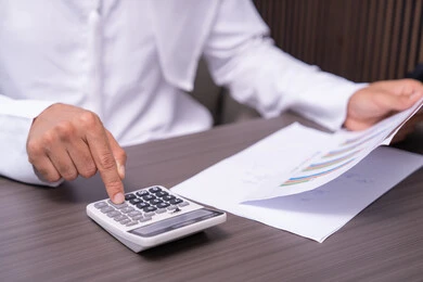 Evaluation of statistical data and extraction of results, a close-up image of the hand of an Arab Gulf Emirati man wearing a kandura working on a computer to complete tasks in the office, using a calculator to perform calculations, an office job in Gulf Arab companies.