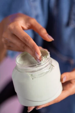 The use of creams and cosmetic ingredients, the concept of caring for the freshness and improvement of the skin, attention to elegance and external appearance, a close-up portrait of the hand of a Saudi Gulf Arab woman holding a hand moisturizing cream, colorful background.