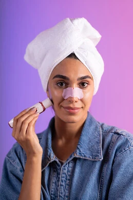 التخلص من حب الشباب باستخدام جهاز الشفط، مفهوم العناية والإهتمام بنضارة وتحسين البشرة، ماسك تنظيف المسام، بورترية مقرب لإمرأة عربية خليجية سعودية ترتدي الزي الكاجوال تضع منشفةالرأس تستخدم لصقات الأنف للتخلص من الرؤوس السوداء والجلد الميت، خلفية ملونه