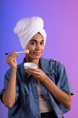 استخدام عسل النحل والمنتجات الطبيعية للعناية بالبشرة، ايماءات السرور والسعادة، اتباع حمية غذائية، منتج وطني محلي سعودي، بورتريه مقرب لامرأة عربية خليجية سعودية مبتسمة ترتدي الزي الكاجوال ومنشفة بيضاء تحمل بيدها ملعقة خشبية مغمورة بالعسل، خلفية ملونه