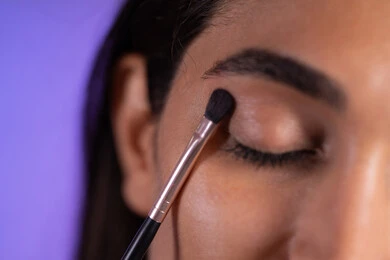 الإهتمام بالجمال والمظهر الخارجي ، التسويق لمنتجات التجميل، إستخدام إحدى أدوات التجميل ( فرشاة ظل العيون ) ، بورتريه مقرب لامراة عربية خليجية سعودية ترتدي الزي الكاجوال تضع ميكاب، أدوات مكياج تتوريال ، خلفية ملونه