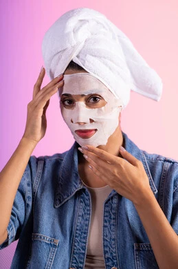 مفهوم العناية والاهتمام بالمظهر الخارجي عند النساء، استخدام مكون ومستحضر تجميلي، خطوات تنظيف وتقشير البشرة، بورتريه مقرب لامرأة عربية خليجية سعودية ترتدي منشفة الرأس و الزي الكاجوال تقوم بوضع قناع على وجهها، خلفية ملونه