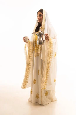 Celebrating national occasions and holidays, the concept of generosity and hospitality, the day we began in 1727 AD, the anniversary of the establishment of the first Saudi state on February 22, a portrait of an Arab Gulf Saudi girl wearing a white abaya pouring coffee from a brass coffee pot, full-body image, white background.