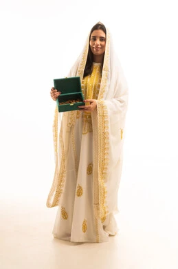 The anniversary of the establishment of the first Saudi state is February 22, celebrating national occasions and holidays, distinctive aromatic scents, a portrait of a young Arab Gulf Saudi woman wearing a white abaya holding a box made of oud wood in her hand, the day we began in 1727 AD, full-length body, white background.