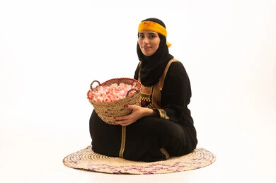 ذكرى تأسيس الدولة السعودية الاولى 22 فبراير، مفهوم حب الوطن والانتماء اليه، المناسبات والأعياد الوطنية، بورتريه لشابة عربية خليجية سعودية ترتدي الشيلة والسدرة تجلس على حصيرة من القش تحمل بيدها سلة مليئة بالورد الجوري الطبيعي، يوم بدينا 1727 م، خلفية بيضاء