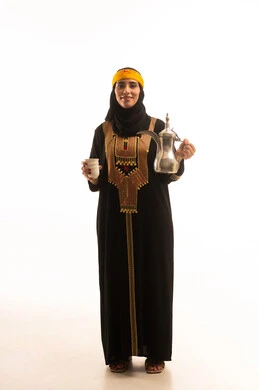 الاحتفال بالمناسبات الوطنية، مفهوم الكرم وحسن الاستقبال، ذكرى تأسيس الدولة السعودية الاولى 22 فبراير، يوم بدينا 1727 م، بورتريه لشابة عربية خليجية سعودية محجبة ترتدي الشيلة والسدرة تنظر الى الكاميرا تقوم بصب القهوة من الدلة النحاسية، صورة الجسم بالطول الكامل، خلفية بيضاء