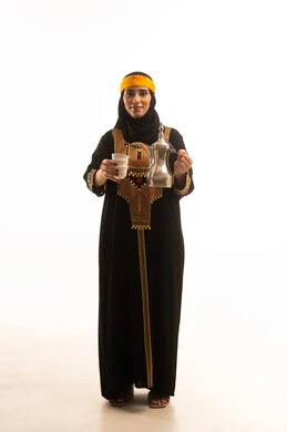 The concept of generosity and hospitality, the anniversary of the establishment of the first Saudi state on February 22, the day we began in 1727 AD, celebrating national occasions, a portrait of a young Arab Gulf Saudi woman wearing a hijab, shayla, and sidra, looking at the camera pouring coffee from a brass dallah, full-body image, white background.