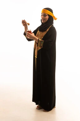 منتجات غذائية مفيدة سعودية، بورتريه من الجانب لامراة عربية خليجية سعودية ترتدي الشيلة والسدره تحمل بيدها ملعقة مغمورة من عسل النحل الطبيعي في وعاء زجاجي، يوم بدينا1727م، إرتداء أزياء المنطقة الجنوبية، ذكرى تاسيس الدولة السعودية22 فبراير، تعابير الفخر والسرور، الجسم بالطول الكامل، خلفية بيضاء