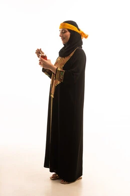 Wearing traditional attire from the southern region, healthy and beneficial food products made in Saudi Arabia, a side portrait of an Arab Gulf Saudi woman wearing the shayla and the sidra, holding a spoon dipped in natural honey in a glass container, on the day we started in 1727 AD, the anniversary of the establishment of the Saudi state on February 22, expressions of pride and joy, full-body shot, white background.