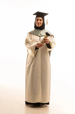 ايماءات البهجة والسعادة بالوصول لحلم النجاح، الاحتفال بإنهاء الدراسة الجامعية، بورتريه لخريجة عربية سعودية خليجية محجبة ترتدي العباءة البيضاء وقبعة التخرج تمسك بيدها وثيقة التخرج, صورة الجسم بالطول الكامل, خلفية بيضاء
