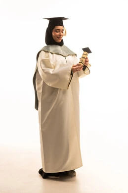 الاحتفال بإنهاء الدراسة الجامعية، ايماءات البهجة والسعادة بالوصول لحلم النجاح, بورتريه لخريجة عربية سعودية خليجية محجبة ترتدي العباءة البيضاء وقبعة التخرج تمسك بيدها وثيقة التخرج, صورة الجسم بالطول الكامل, خلفية بيضاء