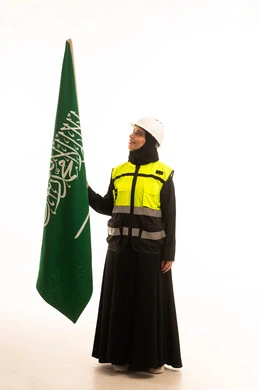 Gestures of pride and honor, participation in the celebration of national occasions and holidays, commemorating the Saudi National Day on September 23, a portrait of an Arab Gulf Saudi engineer wearing an abaya, jacket, and safety helmet holding the flag of the Kingdom of Saudi Arabia, full-body, white background.