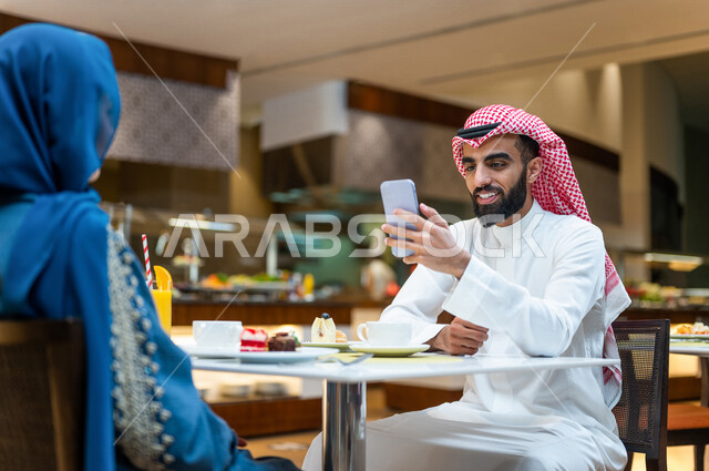 زوجان عربيان سعوديان خليجيان يجلسان في مطعم, الاستمتاع بتناول الطعام, حوارات ونقاشات عائليه, مفهوم الاسره السعيده, قضاء اوقات ممتعه, عطلة نهاية الاسبوع, بناء علاقات وتعارف, صداقات ومعارف