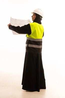 مفهوم الهندسة والإنشاء المعماري، التحقق من تنفيذ المشروع الإنشائي, مهنة ووظيفة نسائية سعودية, بورتريه من الخلف لمهندسة عربية خليجية سعودية محجبة ترتدي العباءة والسترة و خوذة الحماية تمسك بيدها المخطط الهندسي، صورة الجسم بالطول الكامل، خلفية بيضاء