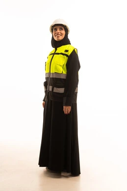 الوقوف بايماءات الثقة، النظر الى شيء ما، العمل في القطاع الهندسي, بورتريه لمهندسة معمارية عربية خليجية سعودية ترتدي خوذة وسترة الحماية تقف باستقامة، صورة لكامل الجسم، خلفية بيضاء