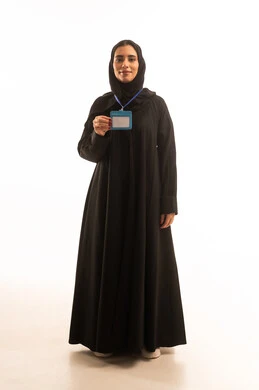 Standing confidently and looking at the camera, wearing a personal badge, displaying an identification card, a blank rectangular white card, a portrait of a smiling Saudi Gulf Arab woman wearing a black abaya and a headscarf holding an ID, full-body image, white background.
