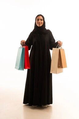 Taking advantage of seasonal offers and discounts, buying supplies and shopping from commercial malls, a portrait of a Saudi Gulf Arab woman wearing an abaya and hijab holding colorful shopping bags, the positive impact of shopping on women, full-body, white background.
