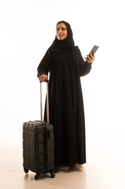 استخدام الأجهزة الحديثة و المتطورة , التجهيز للسفر والرحلات الممتعة, بورتريه لامرأة عربية خليجية سعودية محجبة ترتدي العباءة تمسك بيديها حقيبة السفر والهاتف المحمول, صورة للجسم بالطول الكامل , خلفية بيضاء