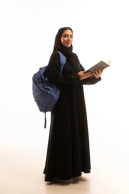 Expressions of diligence and excellence, reviewing lessons for studying and school tests, developing educational curricula in the Kingdom of Saudi Arabia, a portrait of a Gulf Arab Saudi university student wearing an abaya and hijab, reading a school book with focus and engagement, full-body, white background.